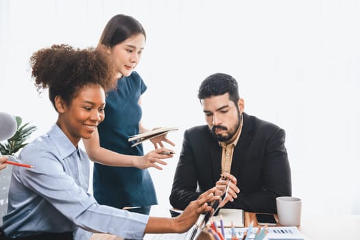 Multiracial analyst team use BI dashboard data to analyze financial report on meeting table. Group of diverse business people utilize data analysis by FIntech for business marketing decision. Concord