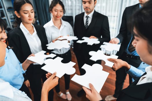 Multiethnic business people holding jigsaw pieces and merge them together as effective solution solving teamwork, shared vision and common goal combining diverse talent. Meticulous