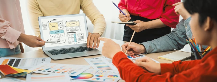 Cropped image of interior designer team discuss the material color while laptop displayed website wireframe designs for mobiles app and website. Creative design and business concept. Variegated.