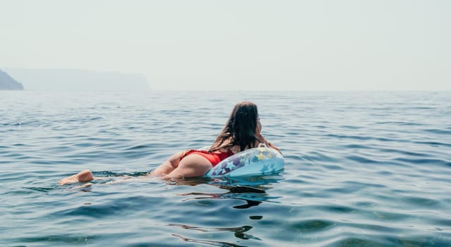 Woman summer sea. Happy woman swimming with inflatable donut on the beach in summer sunny day, surrounded by volcanic mountains. Summer vacation concept