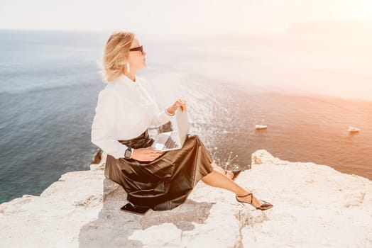 Digital nomad, Business woman working on laptop by the sea. Pretty lady typing on computer by the sea at sunset, makes a business transaction online from a distance. Freelance, remote work on vacation