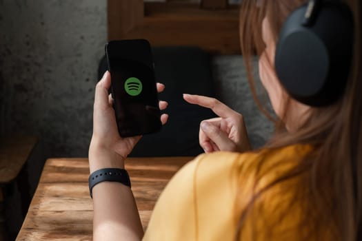 CHIANG MAI, THAILAND - NOV 16, 2023: Person holding a brand new Apple iPhone 14 with Spotify logo on the screen. Spotify is a popular commercial music streaming service..