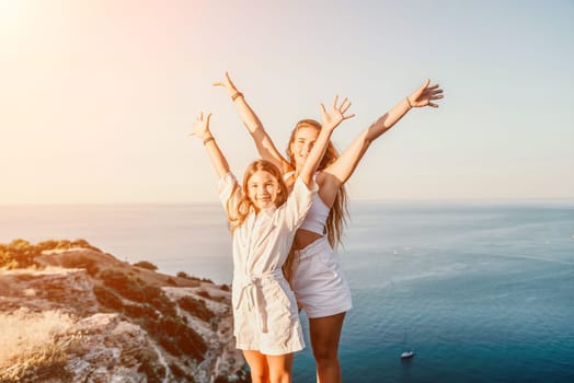 Close up portrait of mom and her teenage daughter hugging and smiling together over sunset sea view. Beautiful woman relaxing with her child.