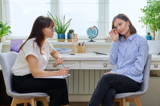 Sad stressed young woman in therapy with professional psychologist. Women talking in office, therapist counselor psychotherapist working with patient. Support, mental health, psychology, psychotherapy