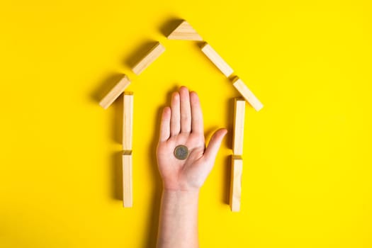 Top view of child's hand close up build blocks showing mince money, house, wooden hut