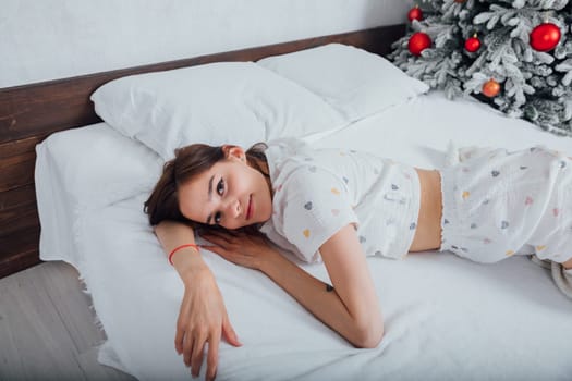 woman in pajamas on bed by christmas tree