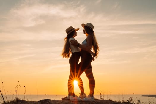 Mother daughter sunset. Mother and daughter stand on the beach, hugging and looking at each other enjoying the sunset