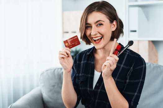 Young happy woman buy product by online shopping at home while ordering items from the internet with credit card online payment system protected by utmost cyber security from online store platform