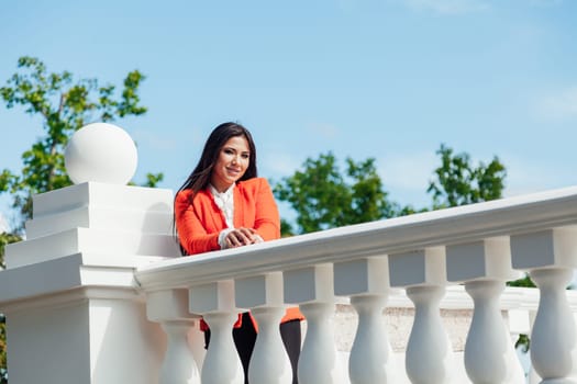 brunette woman standing near the white railing in the park for a walk