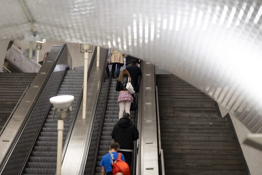 Escalator of metro - woman in short skirt riding up - telephoto