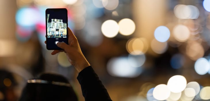 Woman photos on Smartphones new year lights on street - close up