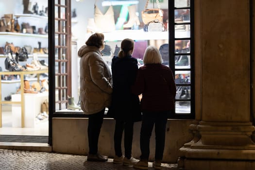 Three women standing in front of a store window