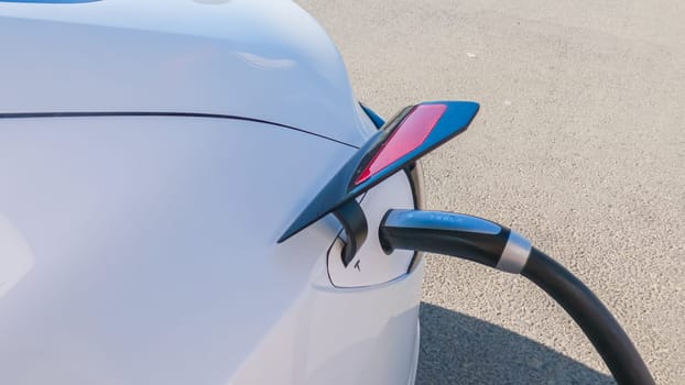 Baker, California, USA-December 3, 2022-During the day, a Tesla vehicle is seen charging at a Tesla Supercharging station, utilizing the high-speed charging infrastructure for convenient and efficient electric vehicle refueling.