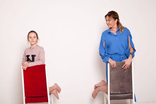 Mom and daughter posing near chairs Family