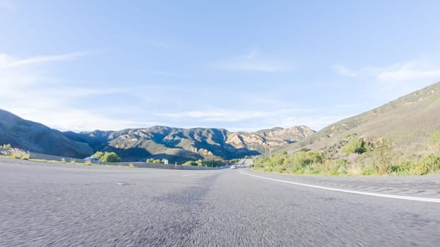 Under a clear blue sky, driving on HWY 101 near California's El Capitan State Beach during the day offers captivating views of the scenic coastal surroundings.