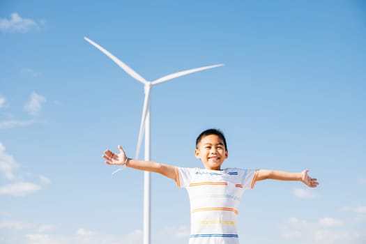 A happy boy in a wind farm's environment. Family joy and carefree moments near turbines celebrating nature's escape and clean energy. The child's smiling face amid windmill technology.