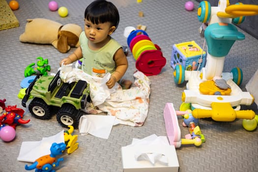 A mess in the children's room, a lot of toys in the children's room. Dirty house. Adorable toddlers playing among the many toys at home.