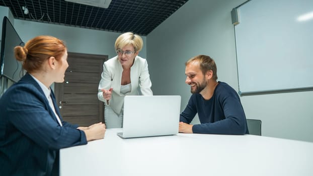 Blond, red-haired woman and bearded man in suits in the office. Business people are negotiating in the conference room