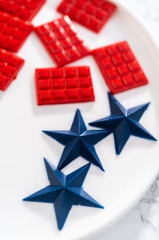Filling silicone mold with red and blue melted chocolate to make chocolate stars for patriotic lemon cupcakes.