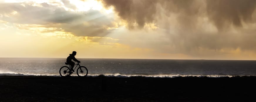 A man riding a bike down a beach next to the ocean
