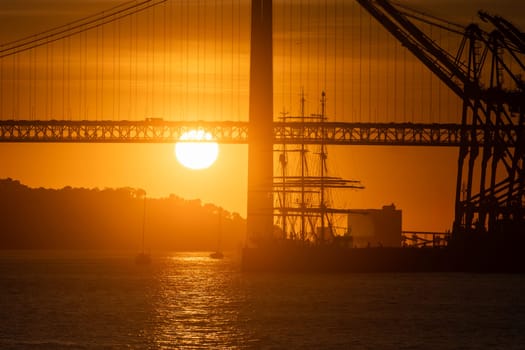 The sun is setting behind a bridge over water