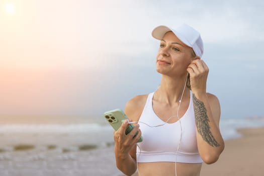 Running woman. Female runner with her smartphone training outdoor workout on beach. Beautiful fit Fitness model outdoors. High quality photo.