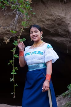 native of ecuador next to a cave touching a green branch. High quality photo