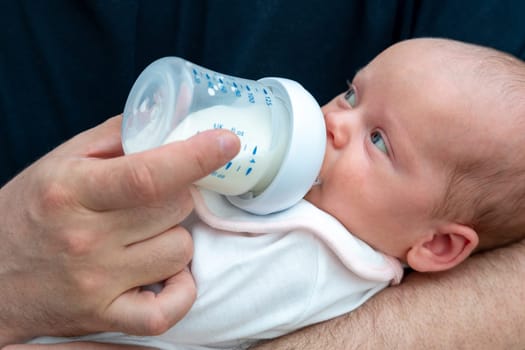 The special connection between a man and his infant is evident as he feeds formula milk from the