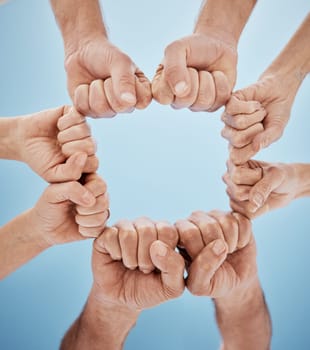 People, hands together and fist bump in teamwork, unity or community below blue sky background. Low angle, closeup or group goals in team building, motivation or support in trust on mockup space.