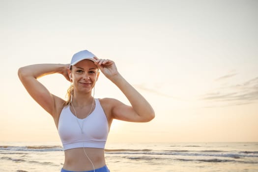 A girl of European appearance in a white cap stands against the background of the sea wearing headphones, there is a place for an inscription High quality photo