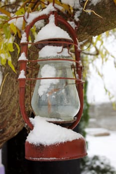 A decorative red glass old lantern decorates a tree with yellow leaves. High quality photo
