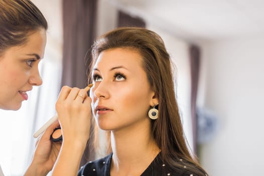 makeup artist applying make up on model.