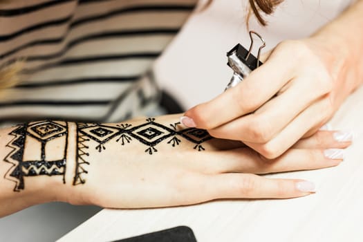 Process of applying Mehndi on female hand close up.