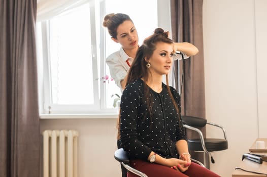 Reflection of hairdresser doing hair style for woman in hairdresser's. Concept of fashion and beauty