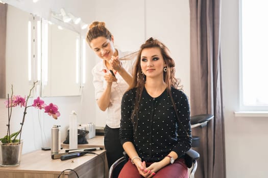 Reflection of hairdresser doing hair style for woman in hairdresser's. Concept of fashion and beauty