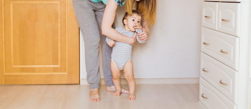 little boy first steps with the help of mom.