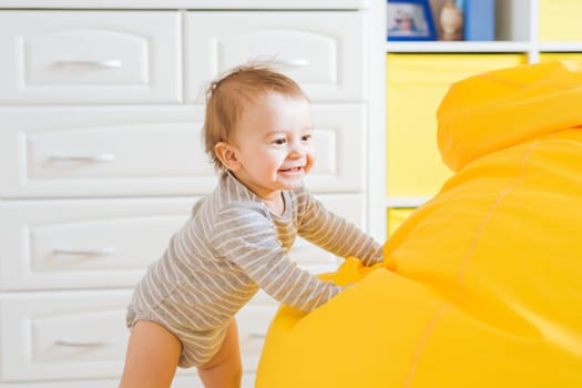 Beautiful adorable laughing baby boy infant face. Smiling child sits on a chair