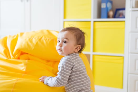 Beautiful adorable laughing baby boy infant face. Smiling child sits on a chair