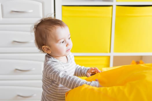 Beautiful adorable laughing baby boy infant face. Smiling child sits on a chair