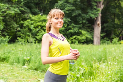 Fit woman outdoors holding a bottle of water.