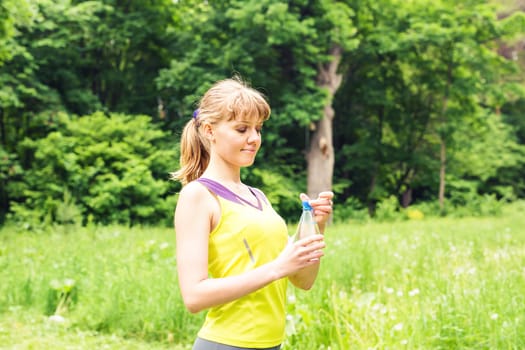 Fit woman outdoors holding a bottle of water.