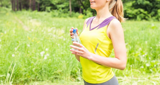 Fit woman outdoors holding a bottle of water.