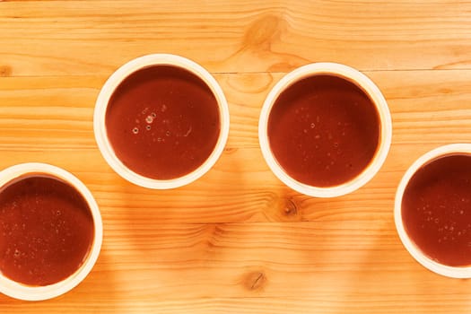 Four bowls with chocolate pudding on  wooden table
