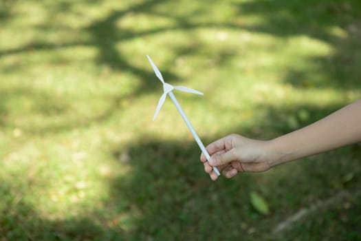 Little boy holding windmill or wind turbine mockup model to promote eco clean and renewable energy technology utilization for future generation and sustainable Earth. Gyre
