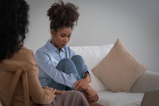 Sad PTSD woman patient in crucial therapy for mental health with psychologist, depression or grief after life failure. Frustrated trauma young woman talking to a psychologist about emotion in clinic