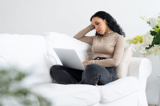 Young African-American woman feels depressed while looking at crucial work in laptop computer