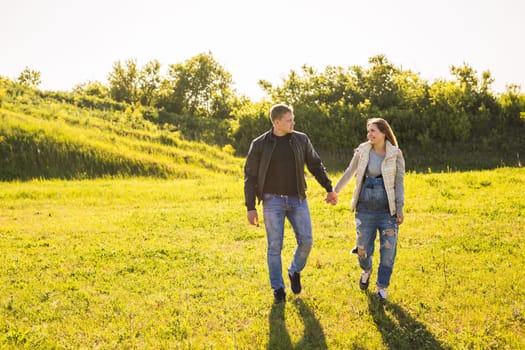 couple holding hands walking in autumn countryside.