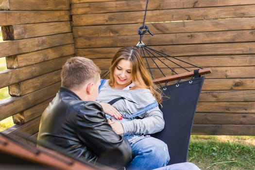 Expectant young loving couple on hammock outdoors