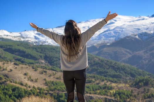 Latina woman opening her arms, enjoying the freedom. she has her back,