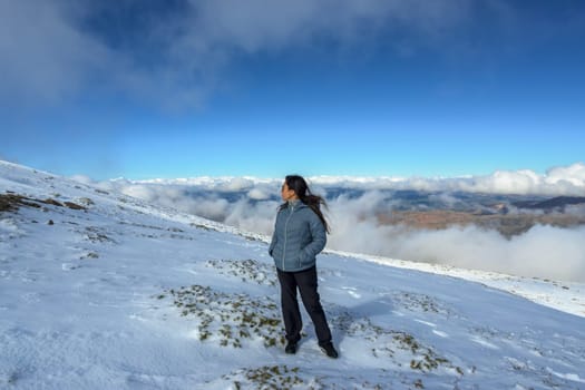 latina woman on mountaintop above the clouds,